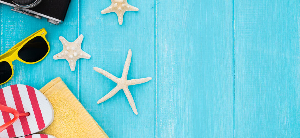 summer-concept-with-vintage-camera-sunglasses-towel-starfish-blue-wooden-background